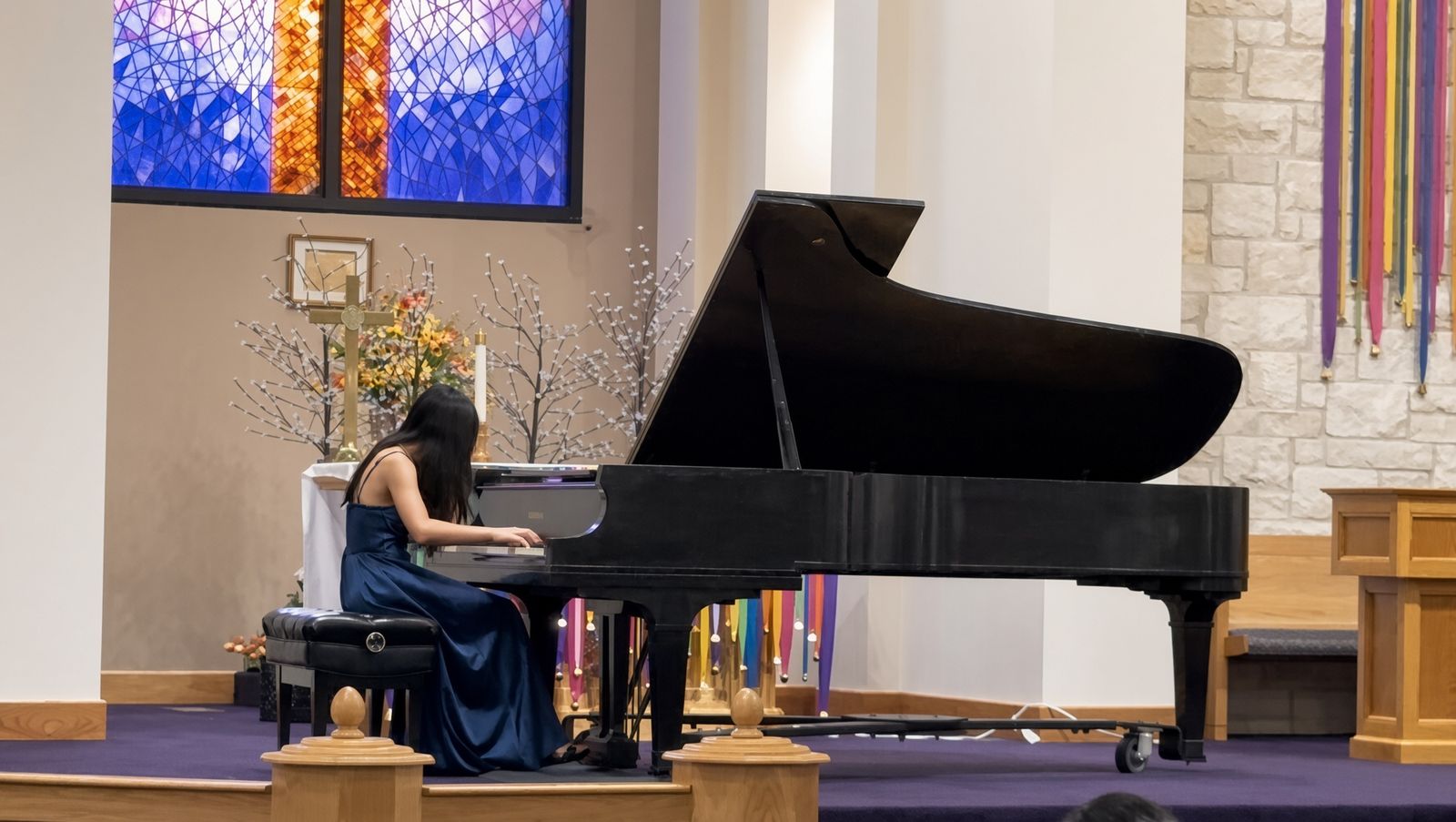Victoria playing grand piano in a stained-glass sanctuary